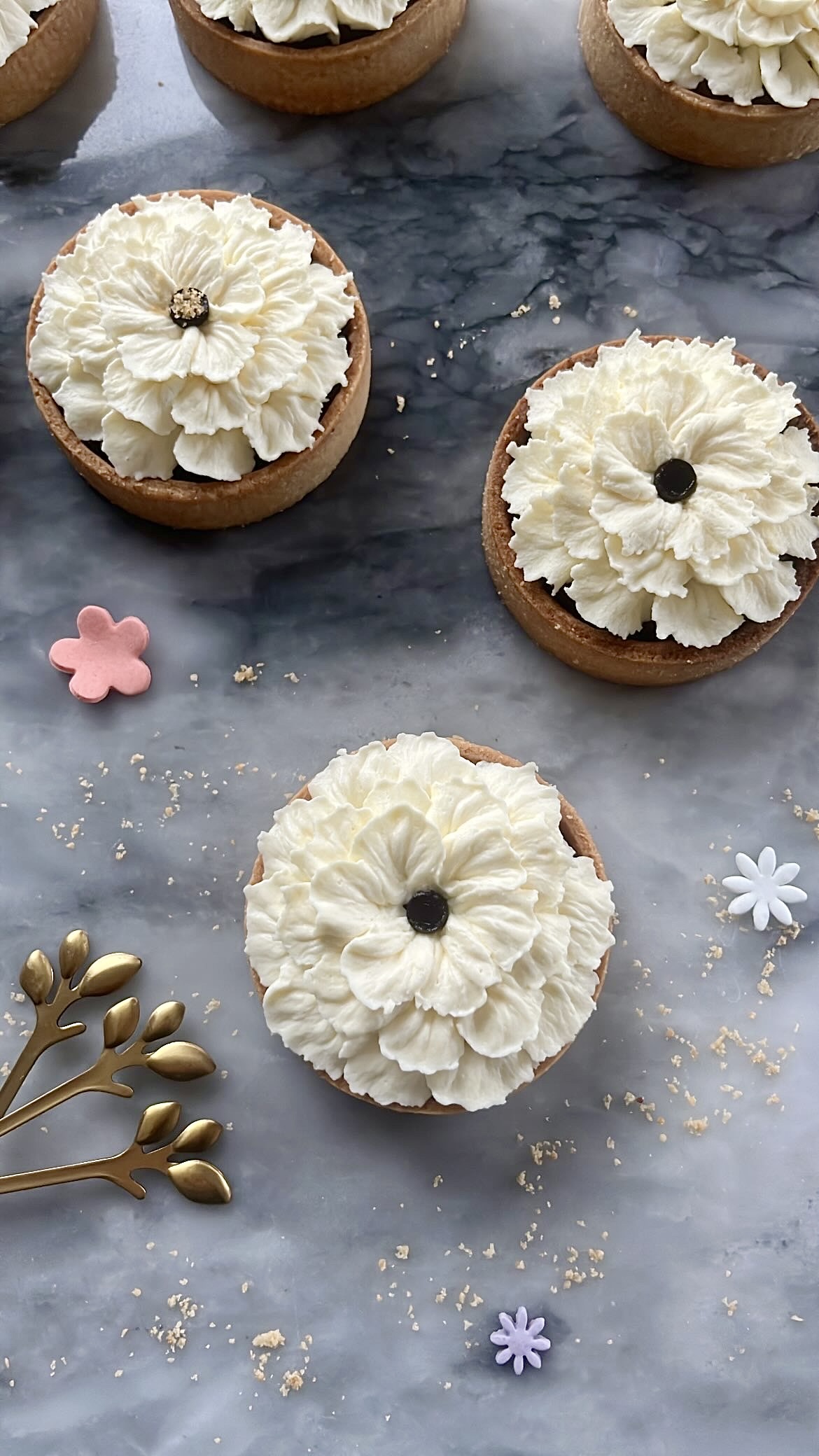 Three tarts decorated with flower-shaped cream piping on top